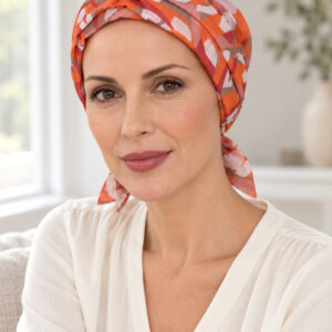 panuelo-naranja-lifestyle Mujer con pañuelo Tibet naranja y coral y blusa marfil junto a una ventana